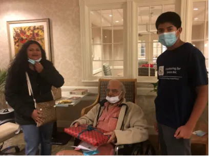 Three people wearing masks, elder in wheelchair