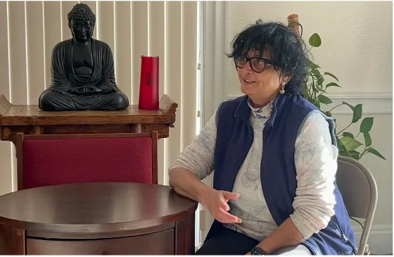 Woman sitting and talking beside Buddha statue