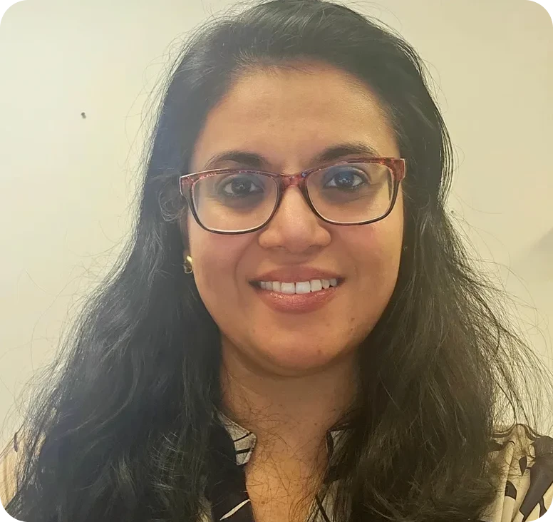 Woman with glasses and dark hair smiling.