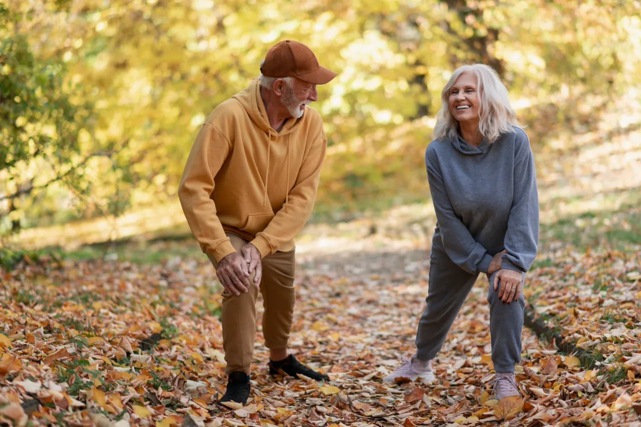 Senior couple stretching on autumn leaf path
