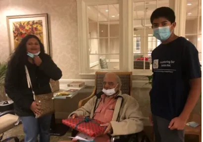 Three people wearing masks, elder in wheelchair