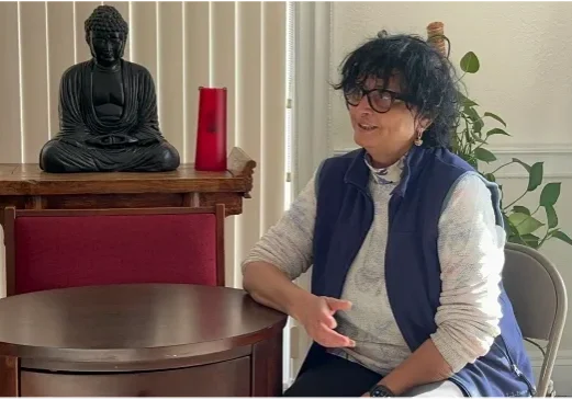 Woman sitting and talking beside Buddha statue
