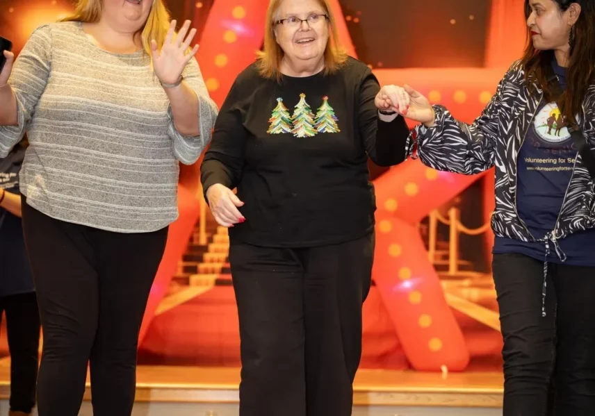 Three women holding hands on stage