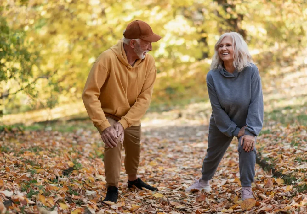Senior couple stretching on autumn leaf path